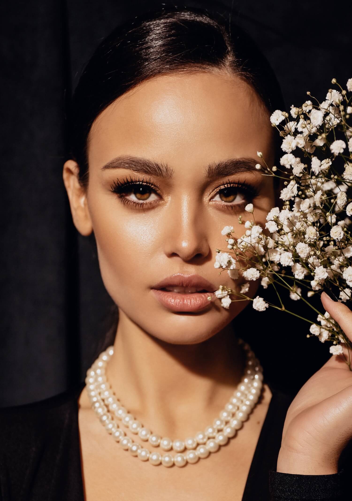 Image of a woman with pearl necklace holding flowers