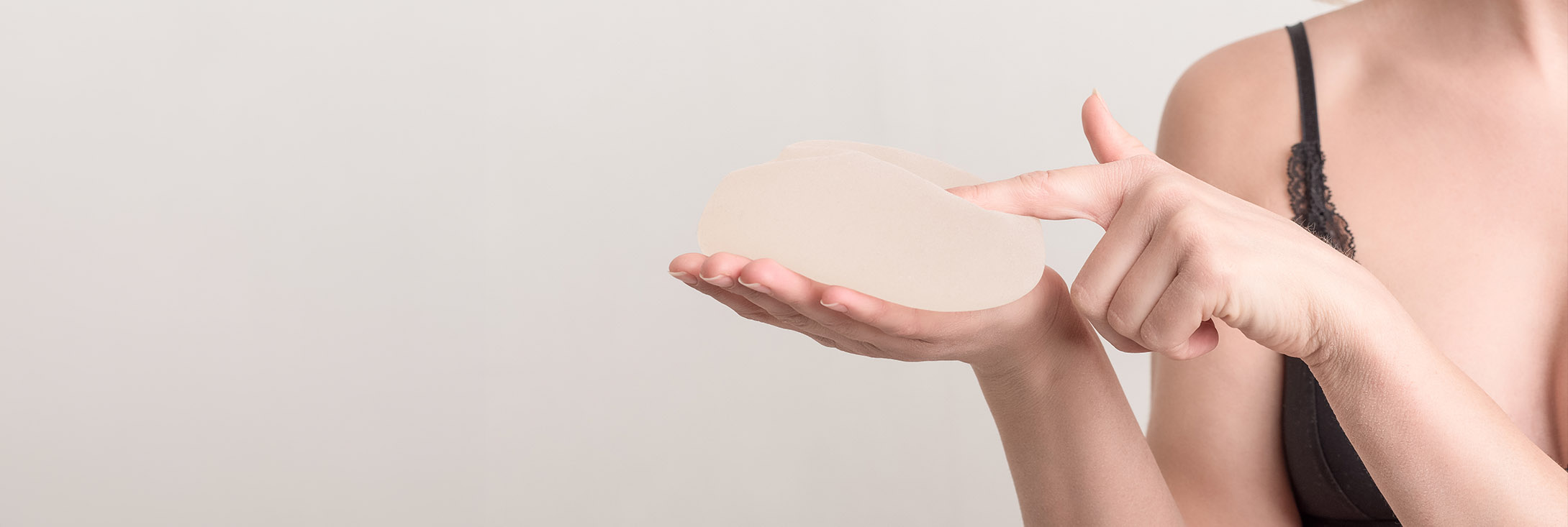 Photo of a woman holding breast implants in her hand