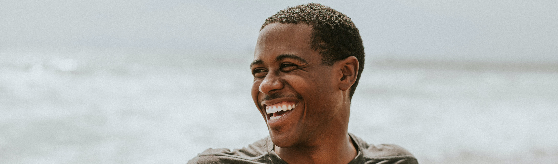 Photo of a smiling man standing in front of ocean water