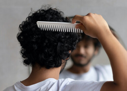 Photo of a man with a full head of hair combing his hair